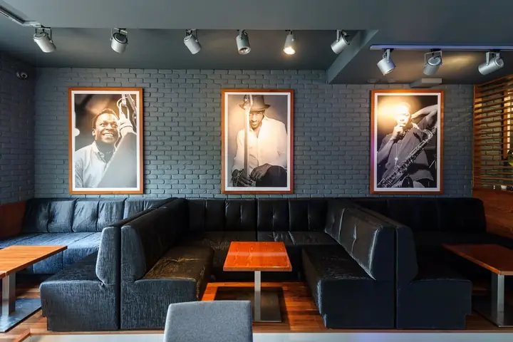 Sala z kanapami i czarno-białymi portretami legend jazzu